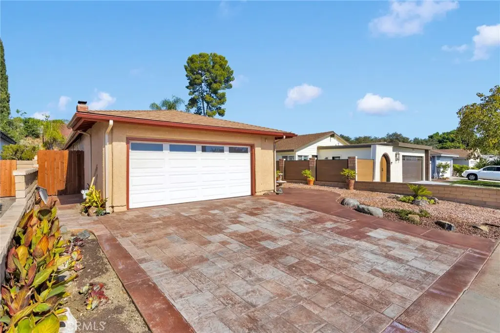 26998 El Retiro, Mission Viejo: cream stucco single-story ranch with terracotta tile roof, paver driveway, and drought-tolerant front landscaping under a clear California sky.